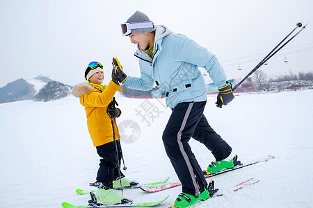 父子玩耍滑雪场上击掌的快乐父子背景