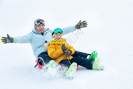 兴奋无忧无虑厚衣服快乐父子坐着雪上滑板滑雪图片
