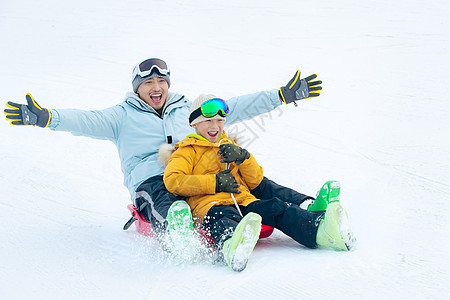 活力快乐父子坐着雪上滑板滑雪图片