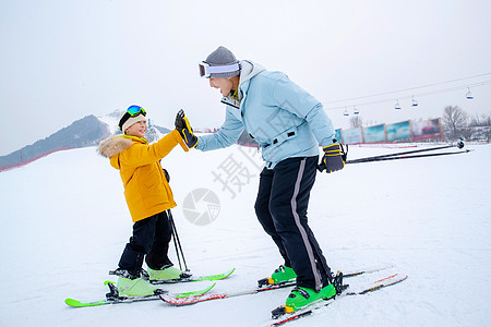滑雪场上击掌的快乐父子高清图片