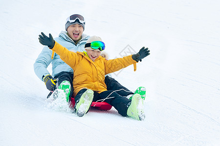 快乐父子坐着雪上滑板滑雪高清图片