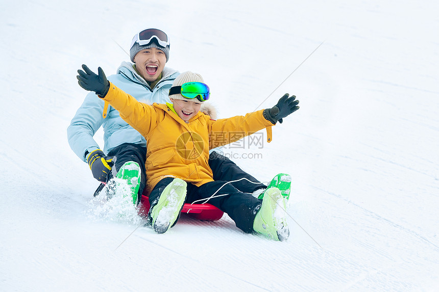 快乐父子坐着雪上滑板滑雪图片
