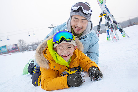 滑雪场内抱在一起打滚的快乐父子图片