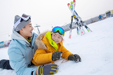 滑雪场内抱在一起打滚的快乐父子高清图片