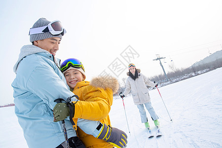 滑雪场上抱在一起的父子和滑雪的母亲图片