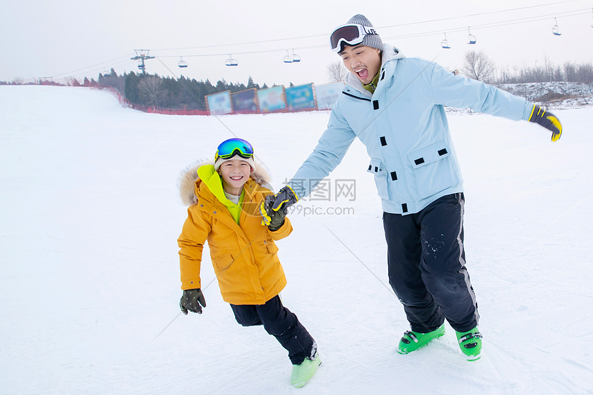 滑雪场内手牵手奔跑的快乐父子图片