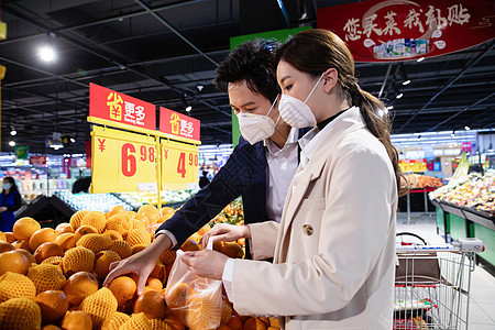 青年夫妇戴口罩在超市挑选水果图片