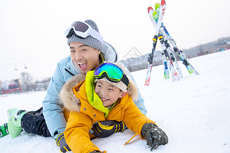 滑雪场内抱在一起打滚的快乐父子图片