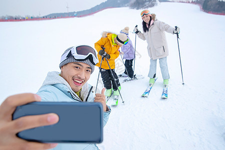 手套户外童年滑雪场上用手机自拍的一家四口图片