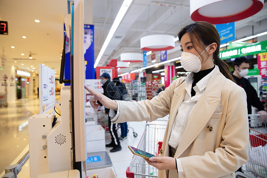 戴口罩的青年女人在超市用手机付款图片
