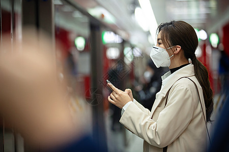 戴口罩的年轻女人站在地铁站台上图片