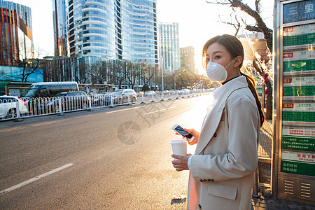 公共交通戴口罩的年轻女人站在公交车站图片