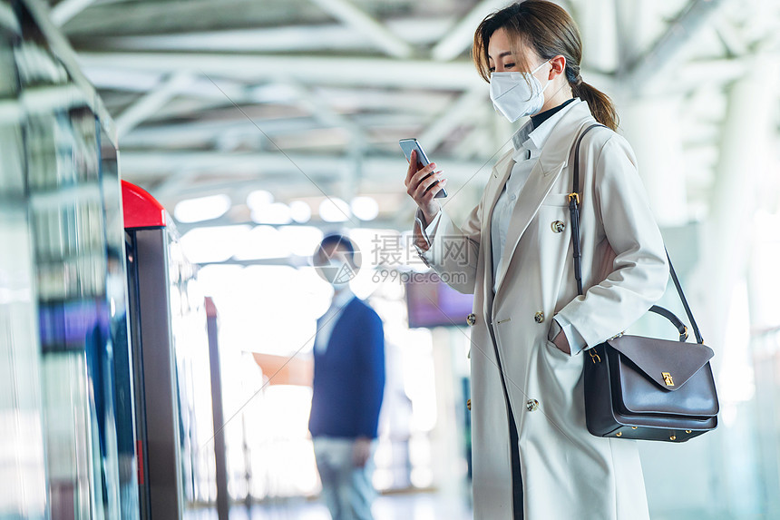 戴口罩的年轻女人站在地铁站台上图片