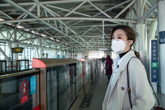 务戴口罩的年轻女人站在地铁站台上图片