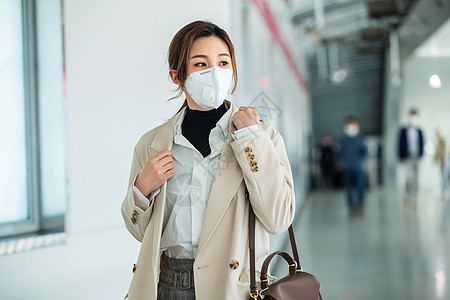 商务戴口罩的年轻女人走在地铁站里图片