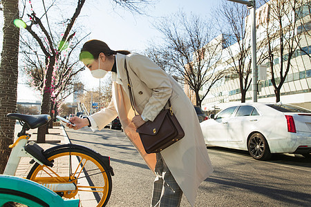 通勤戴口罩的年轻女人扫码骑共享单车图片