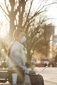 戴口罩的青年女人在户外使用电脑图片