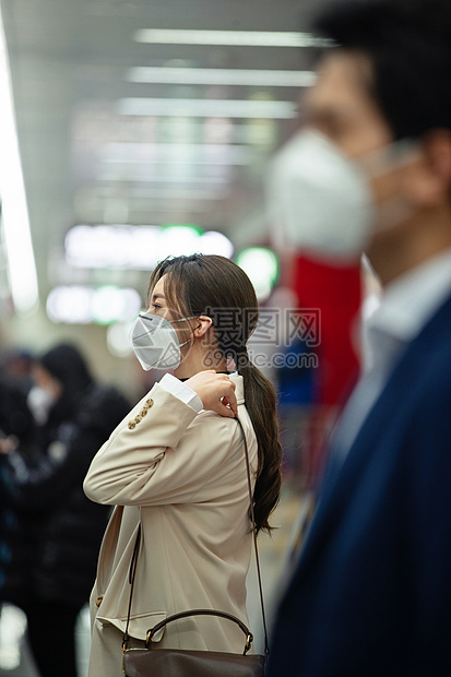 戴口罩的年轻女人站在地铁站台上图片