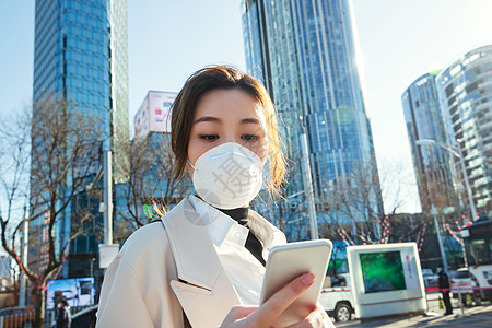 城市楼群白领戴口罩的青年女人看手机背景