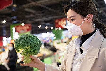 疫情生活戴口罩的青年女人在超市挑选青菜图片