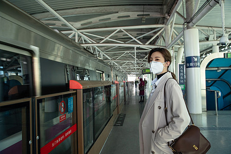 戴口罩的年轻女人站在地铁站台上图片