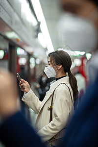 戴口罩的年轻女人在地铁里看手机图片
