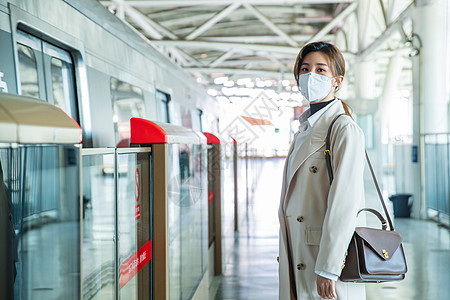 戴口罩的年轻女人站在地铁站台上高清图片