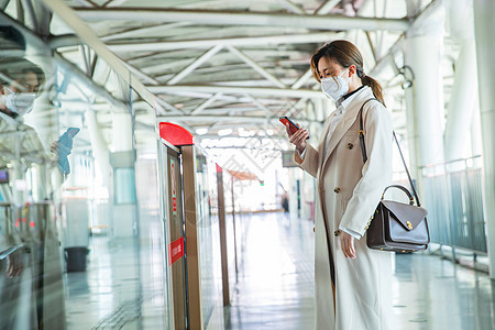 戴口罩的年轻女人站在地铁站台上图片