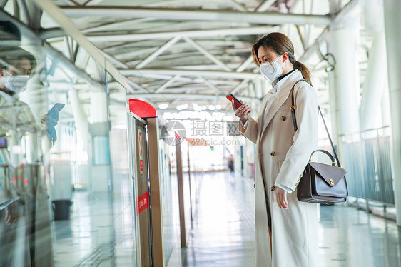 戴口罩的年轻女人站在地铁站台上图片