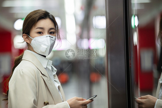 戴口罩的年轻女人站在地铁站台上图片