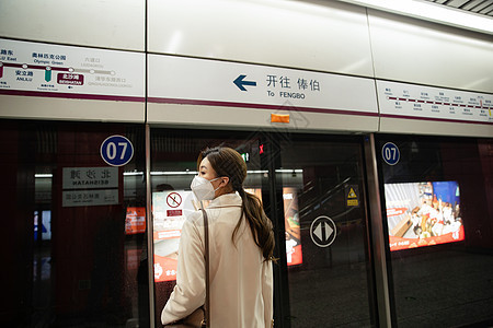 疫情上下班戴口罩的年轻女人站在地铁站台上图片