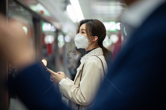 戴口罩的年轻女人站在地铁站台上图片