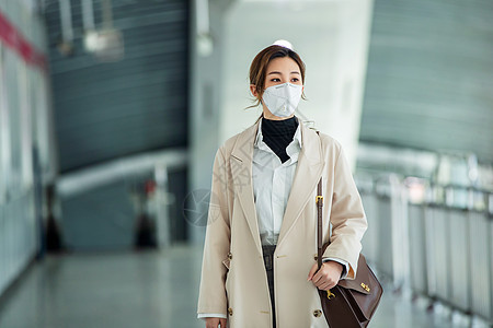 休闲装通勤者女商人戴口罩的年轻女人走在地铁站里背景图片