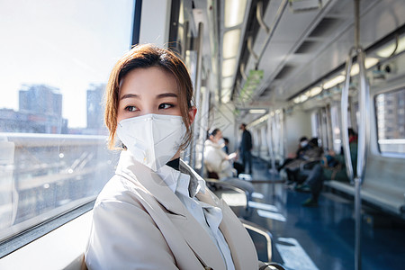 透过窗户往外看戴口罩的年轻女人乘坐地铁图片