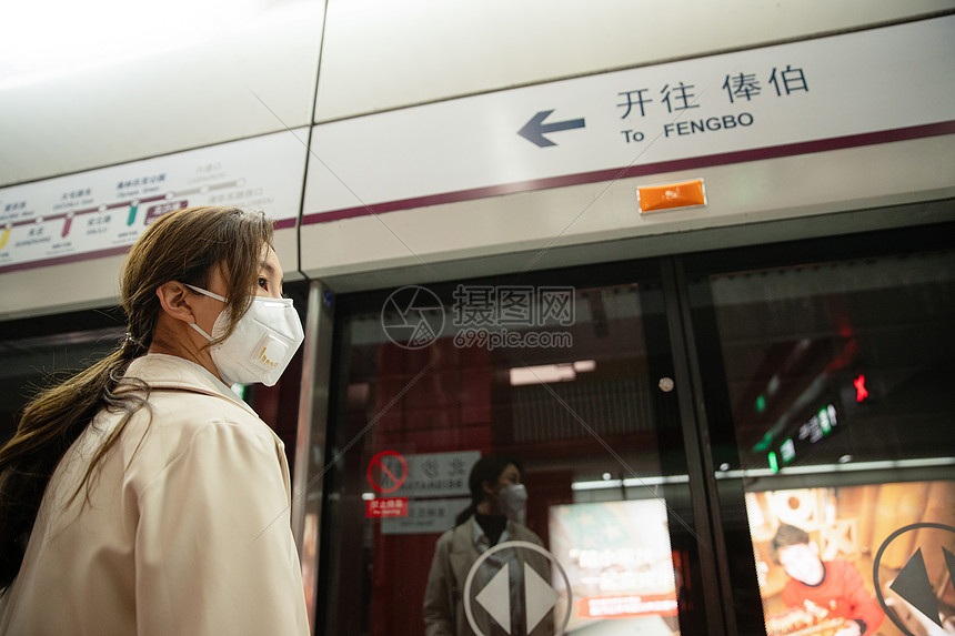 戴口罩的年轻女人站在地铁站台上图片