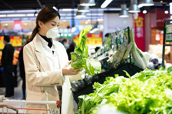 戴口罩的青年女人在超市购买青菜图片