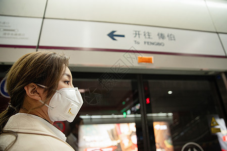 戴口罩的年轻女人站在地铁站台上图片