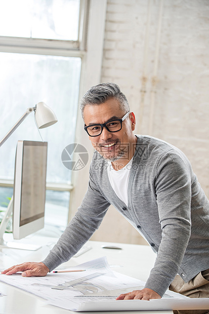 中老年男人窗户眼镜室内画图纸的资深设计师肖像图片