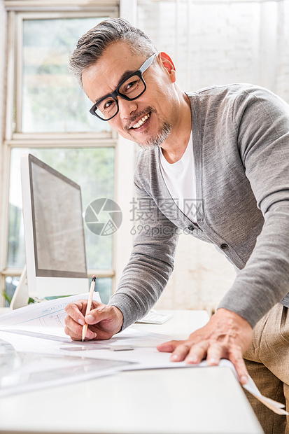 在室内研究图纸的中老年设计师男士图片