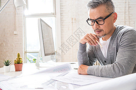 在室内研究图纸的中老年设计师男士图片