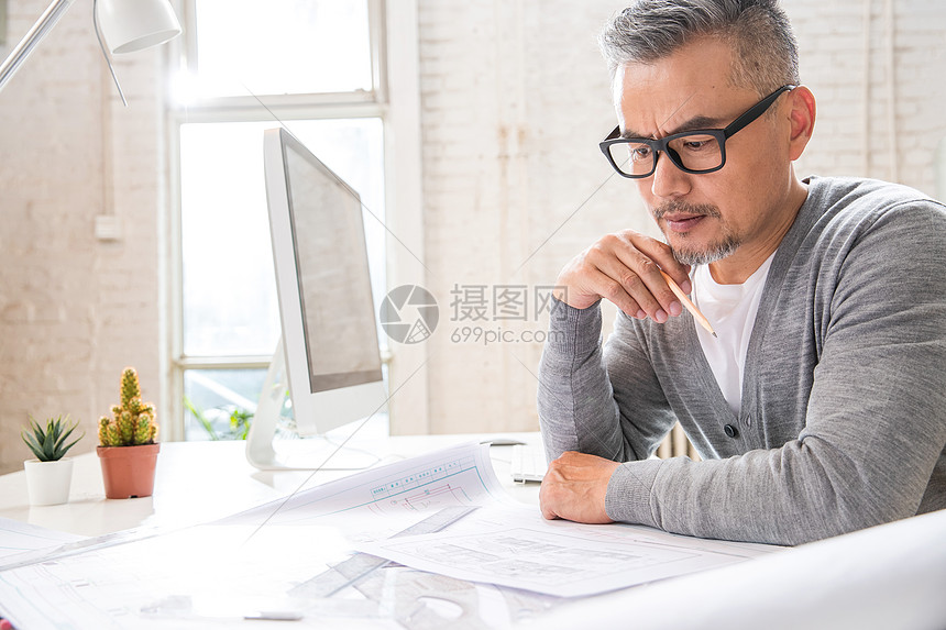 在室内研究图纸的中老年设计师男士图片