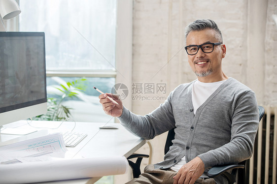 在室内研究图纸的中老年设计师男士图片