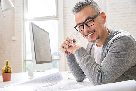 在室内研究图纸的中老年设计师男士图片