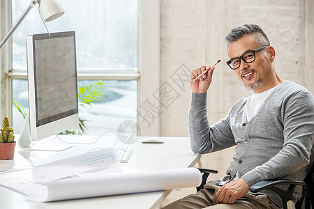 在室内研究图纸的中老年设计师男士图片