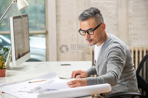 在室内研究图纸的中老年设计师男士图片