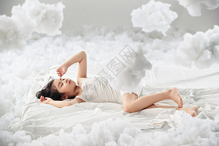 闭上眼睛无忧无虑可爱的小女孩躺在云朵上图片