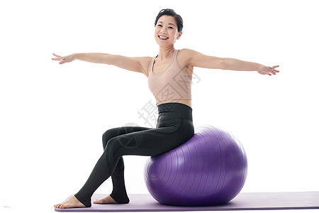 中年女坐在瑜伽球上练习瑜伽图片