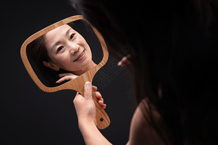 木质享乐手拿镜子拿着镜子照的中年女人图片素材