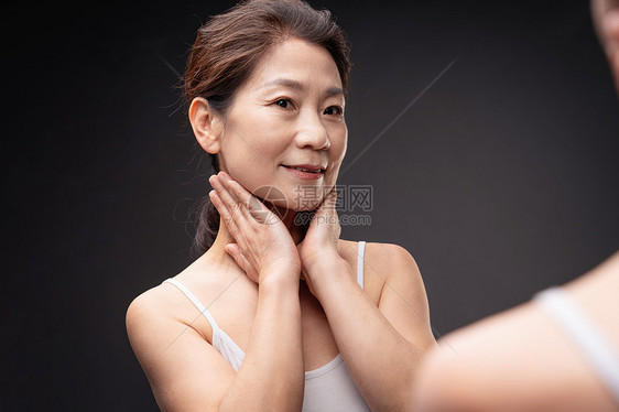 镜子里做颈部护理的中年女图片