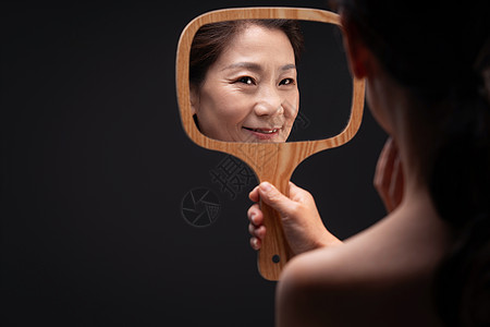 ·拿着镜子照的中年女人图片